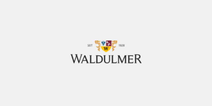 Logo der Marke Waldulmer mit goldenem Wappen, gelbem 'W', Schriftzug ‚Seit 1928‘ und ‚Waldulmer‘ darunter.