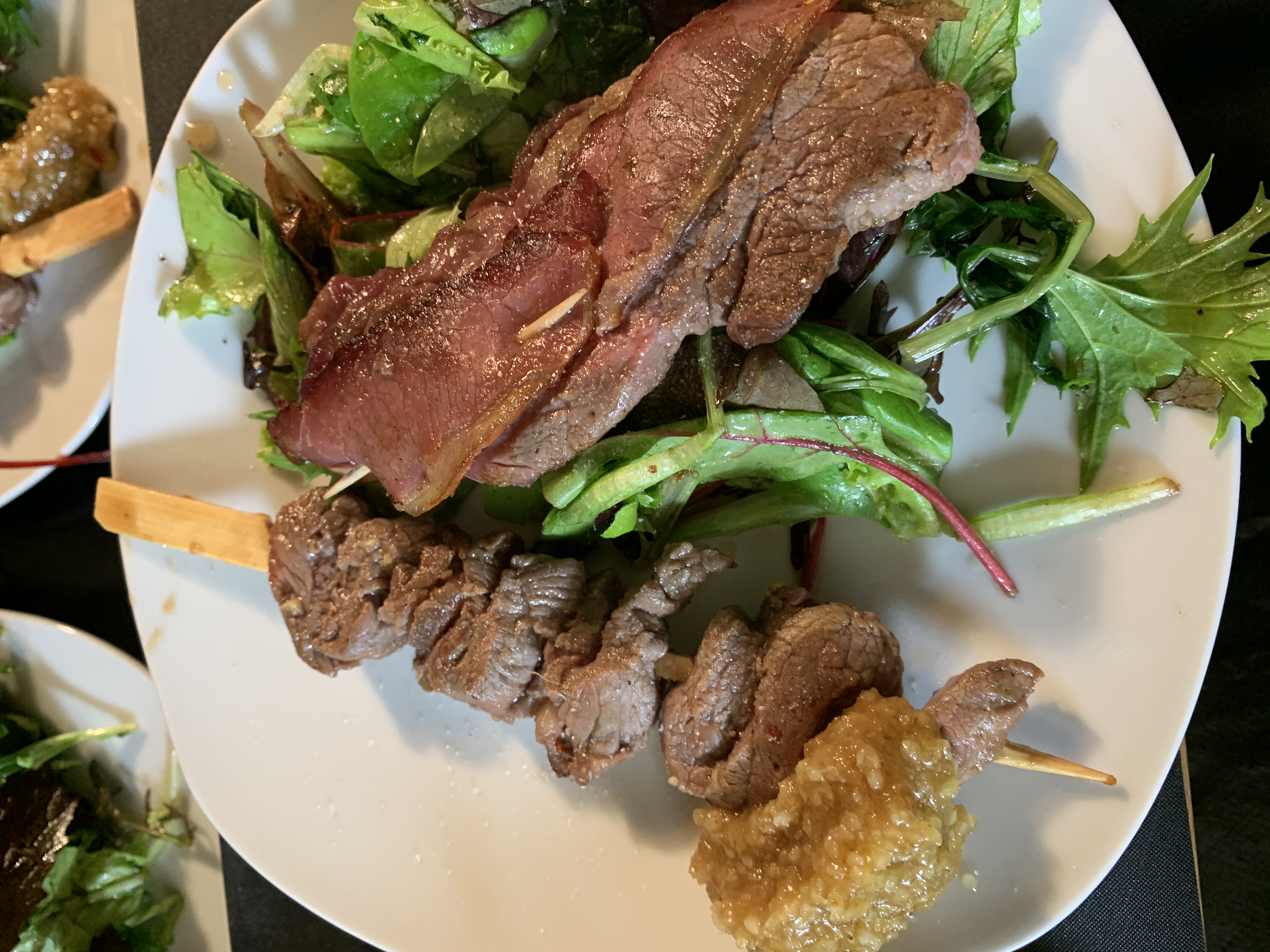 Teller mit zwei Fleischspießen und Blattsalat, gegrillt und dekorativ angerichtet.